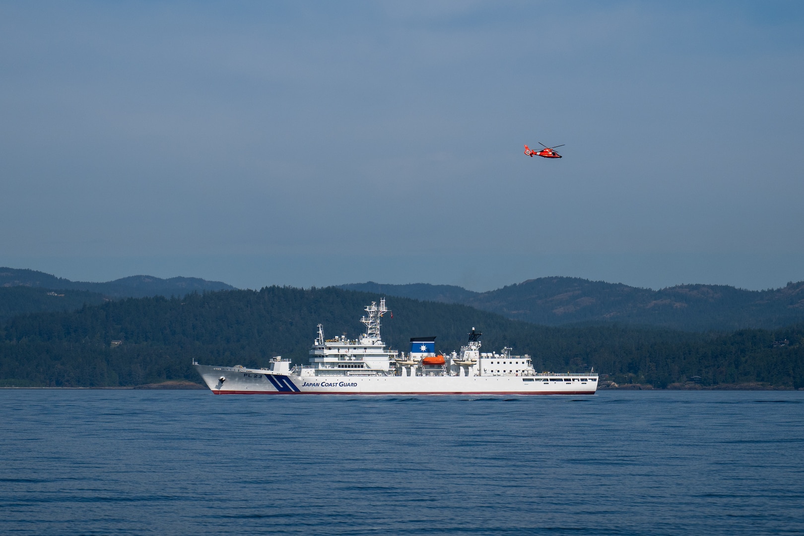 An MH-65 Dolphin helicopter from U.S. Coast Guard Air Station Port Angeles flies over Japan Coast Guard ship Itsukushima during a joint search and rescue exercise in the Strait of Juan de Fuca, May 21, 2026.