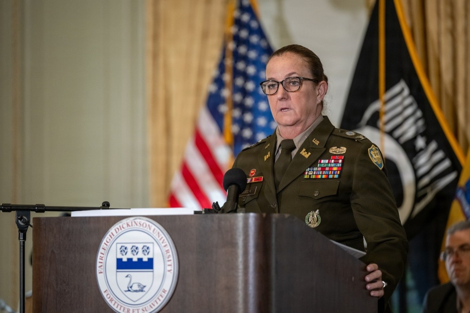 Photo of Army Col. Deanne M. Ojeda standing behind a podium as she addresses recent high school graduates.