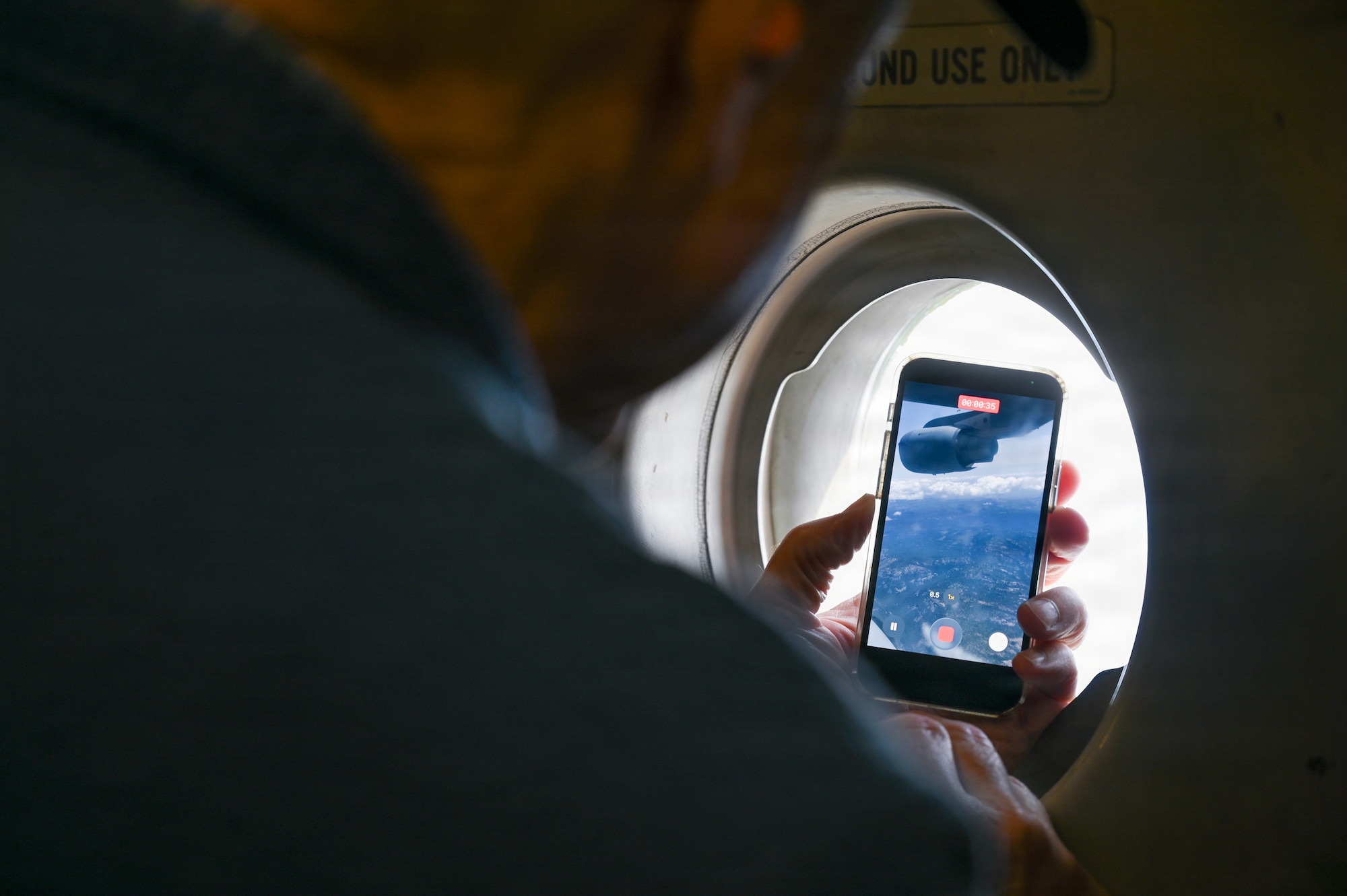 A local Puget Sound civic leader takes a video through a rear door window aboard a 62d Airlift Wing C-17 Globemaster III above central Washington, May 19, 2026.