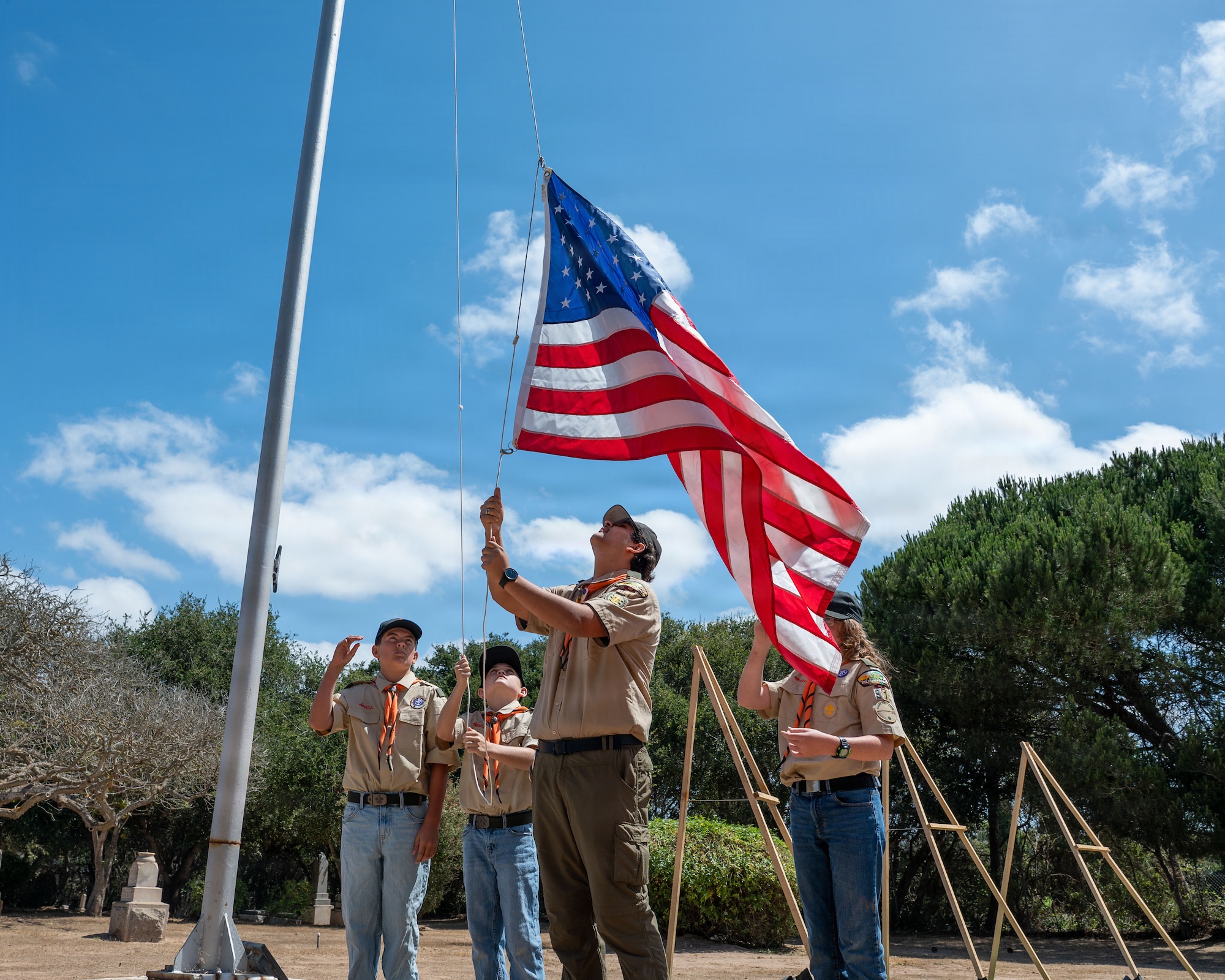 a group of boy scouts raise the flag on a pole
