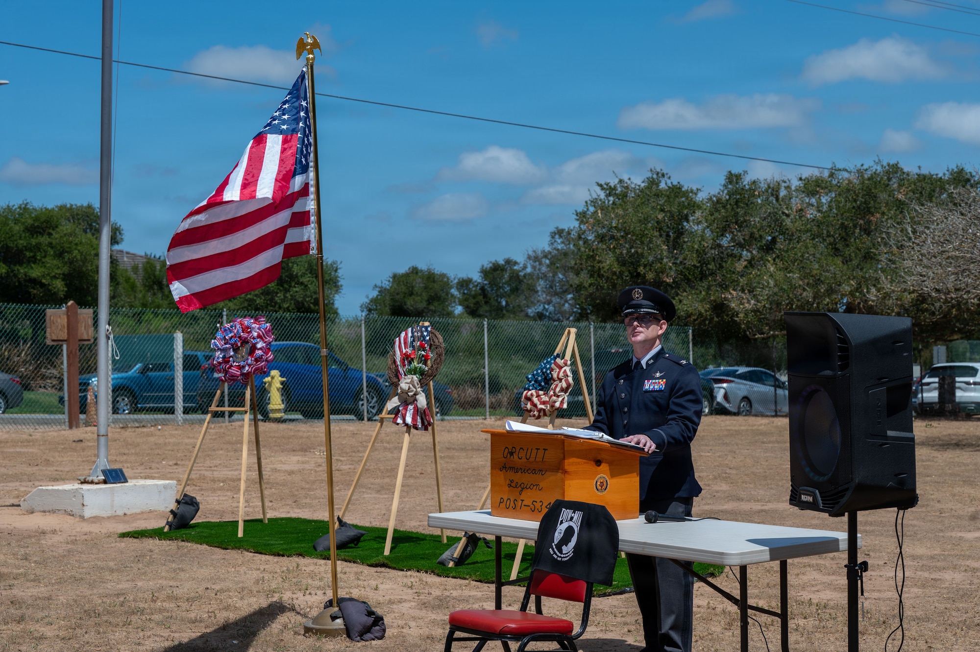 a man stands at a podium in a field of grass and delivers a speech