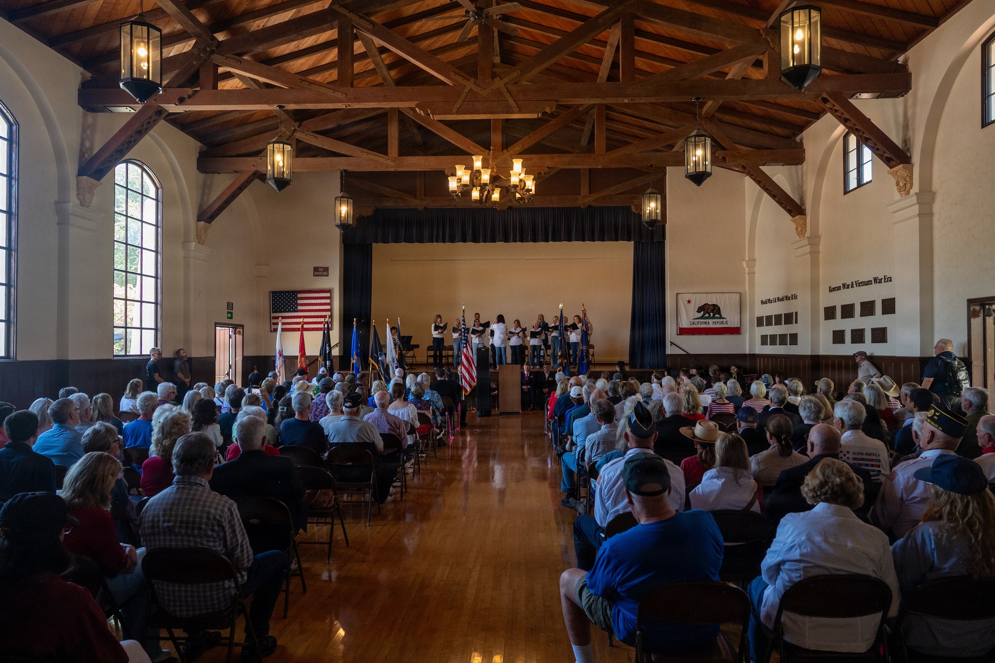 A group of people sit in a large hall during a ceremony.