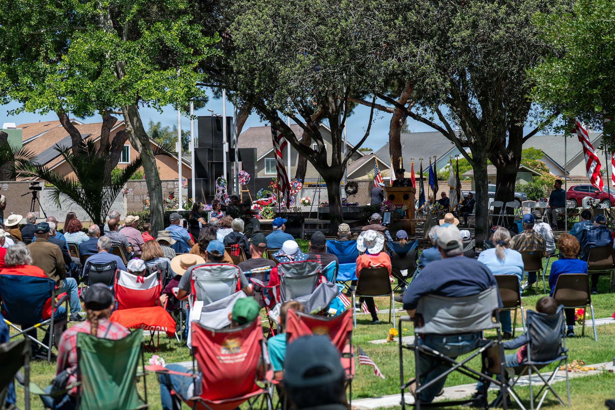 A crowd of people sit and listen to a colonel speak at the Memorial Day ceremony.