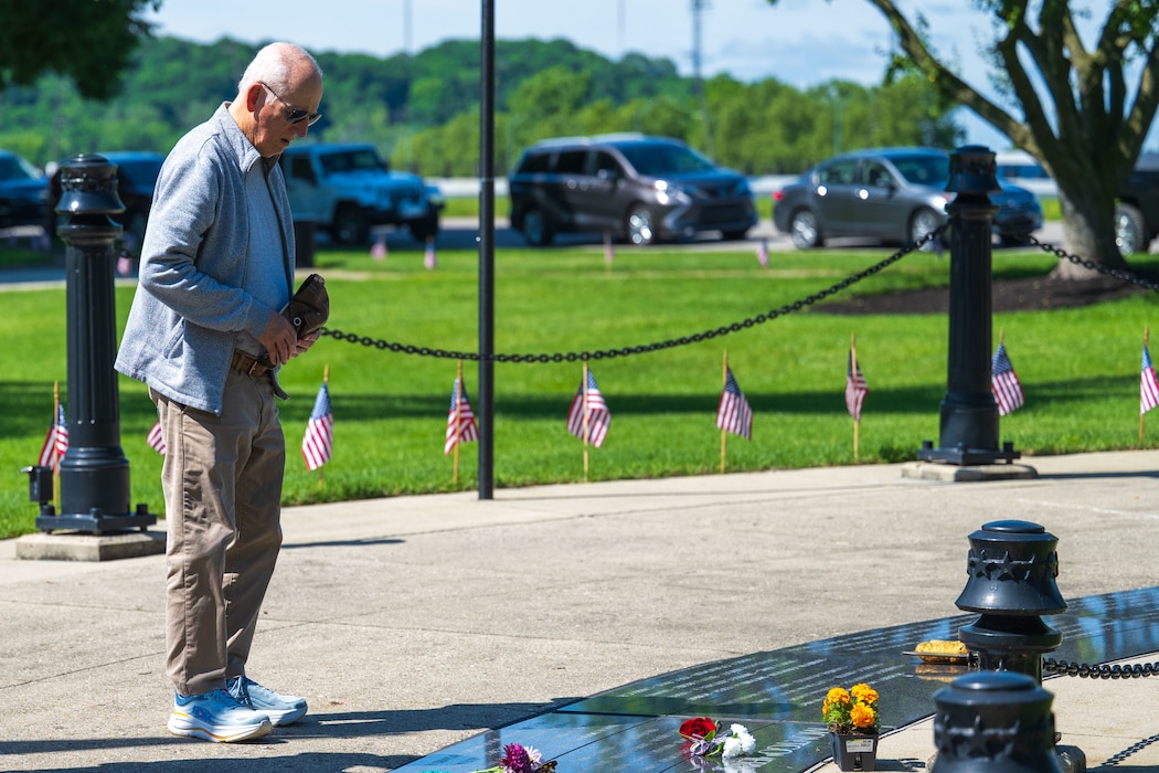 A man stands in reflection beside the Dayton Vietnam Veterans Memorial while honoring a fallen service member.