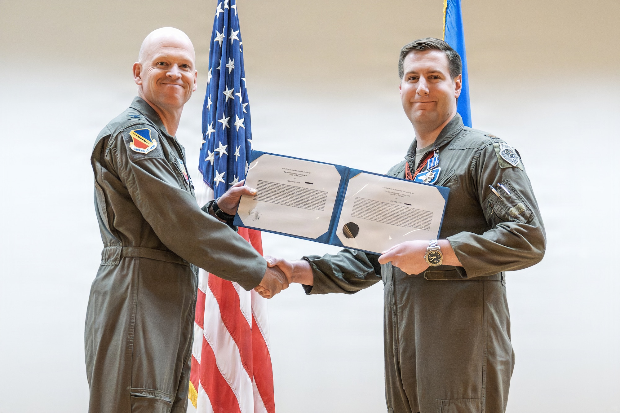A photo of an Air Force officer presenting an award to another military member on stage.