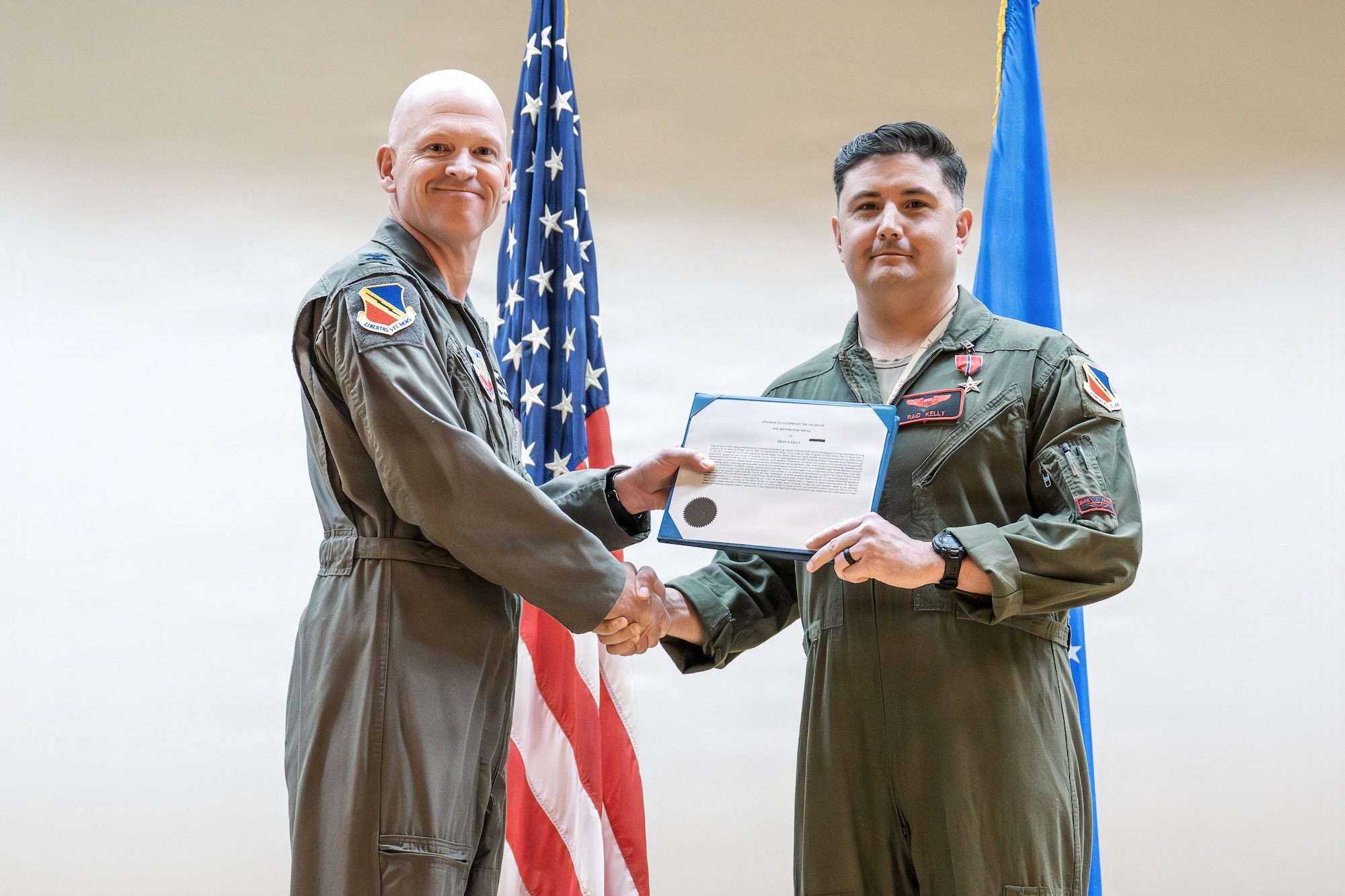 A photo of an Air Force officer presenting an award to another military member on stage.