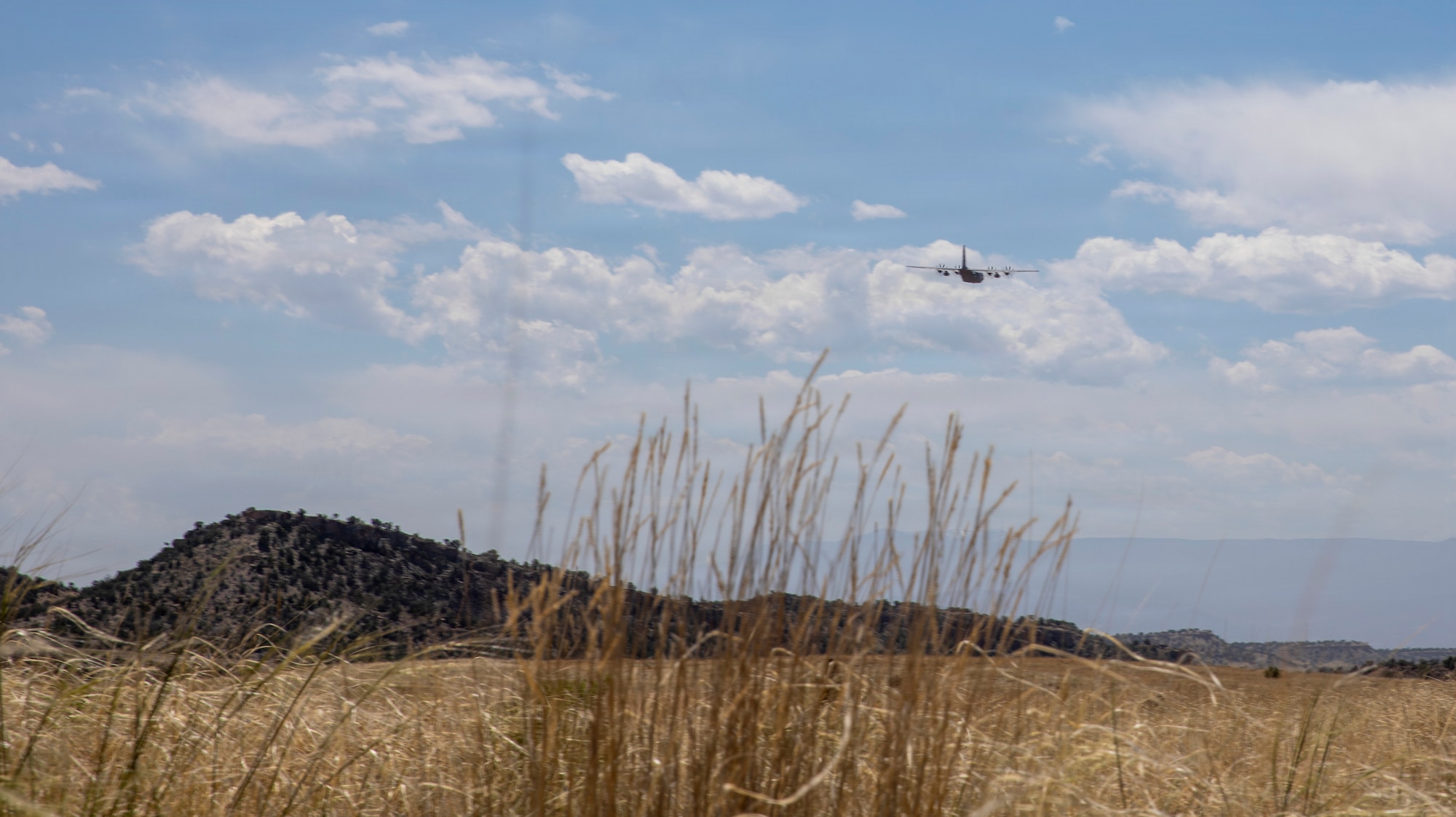 C-130 flies away from dirt landing strip