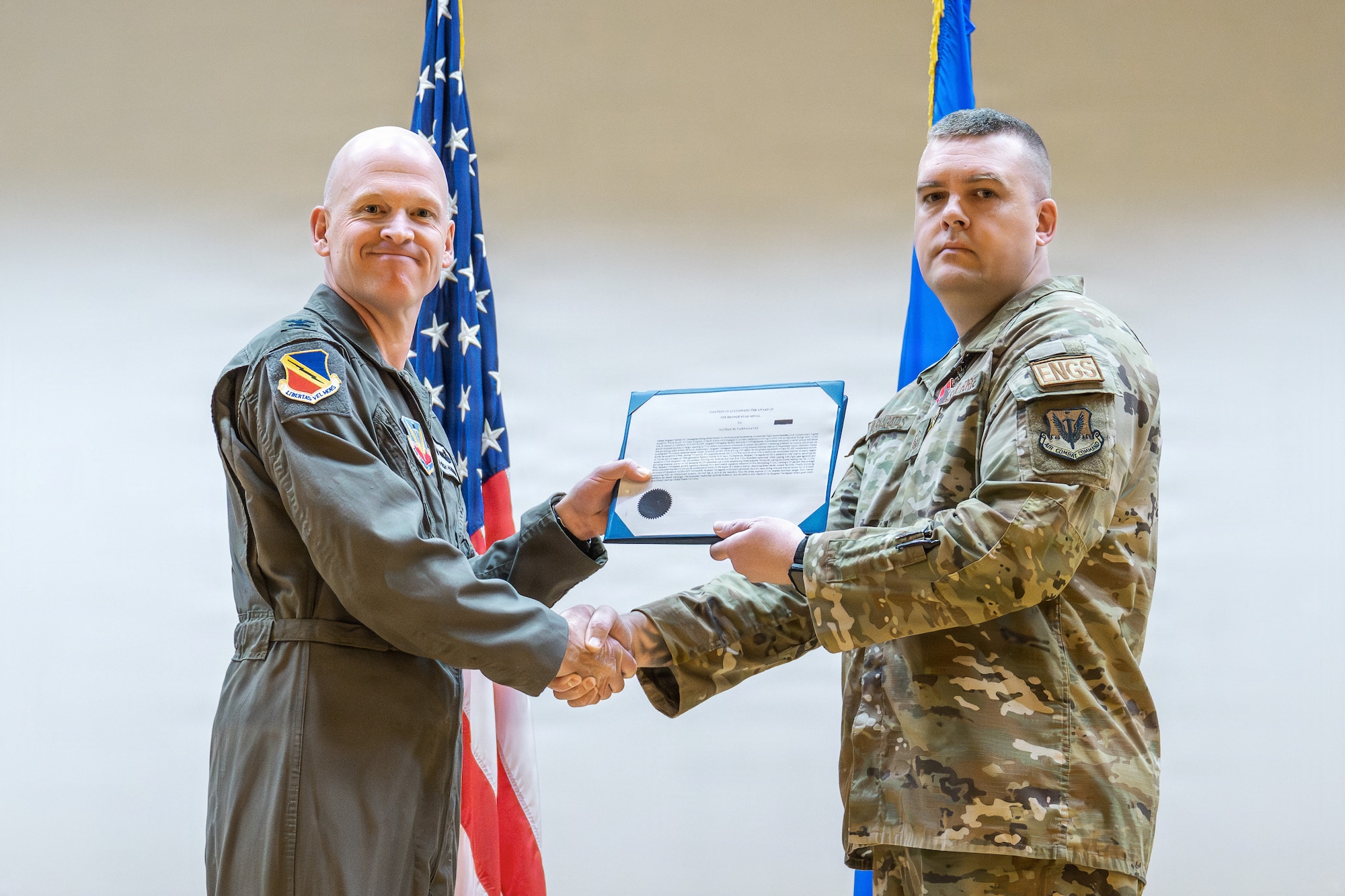 A photo of an Air Force officer presenting an award to another military member on stage.