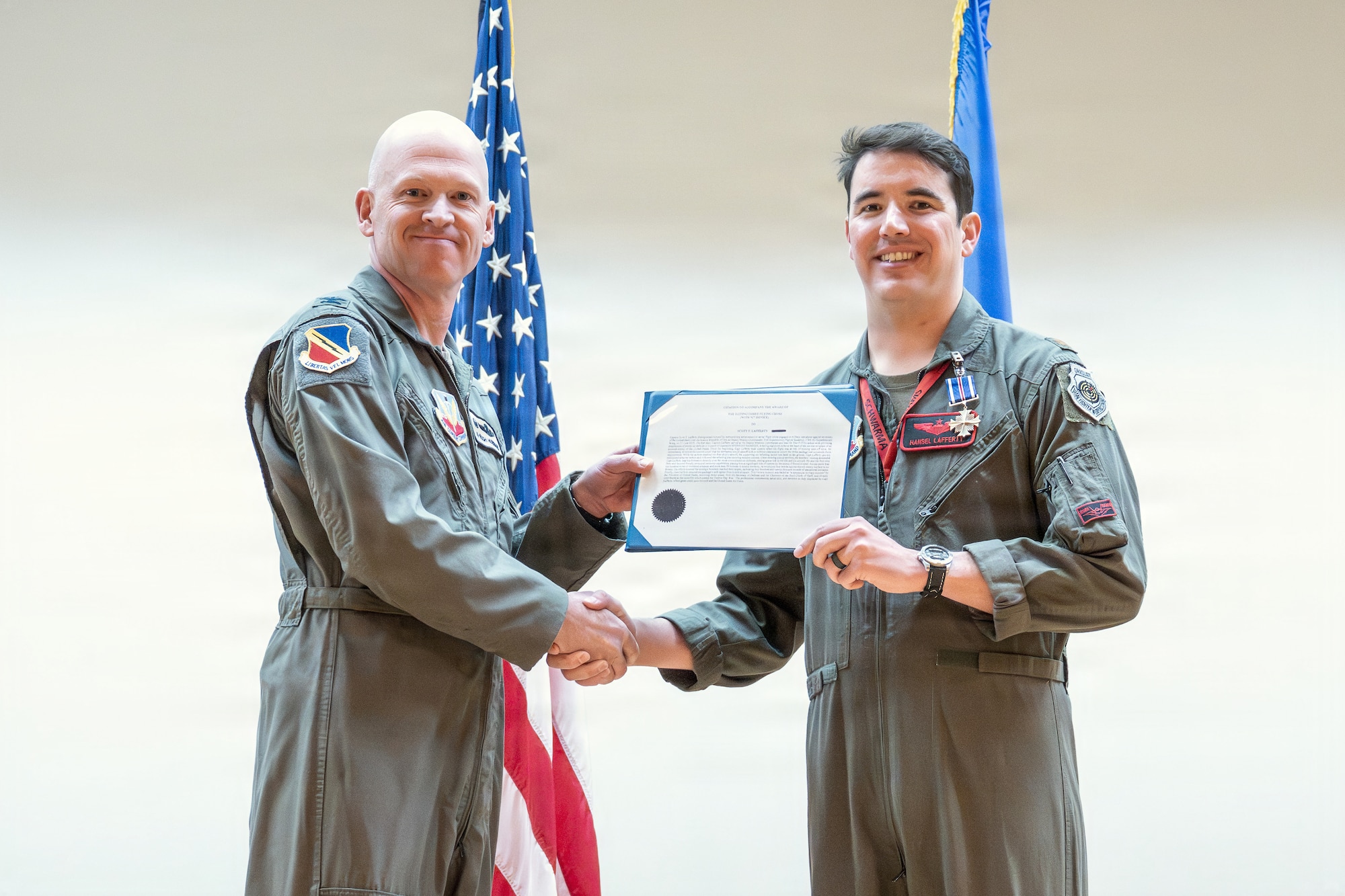 A photo of an Air Force officer presenting an award to another military member on stage.