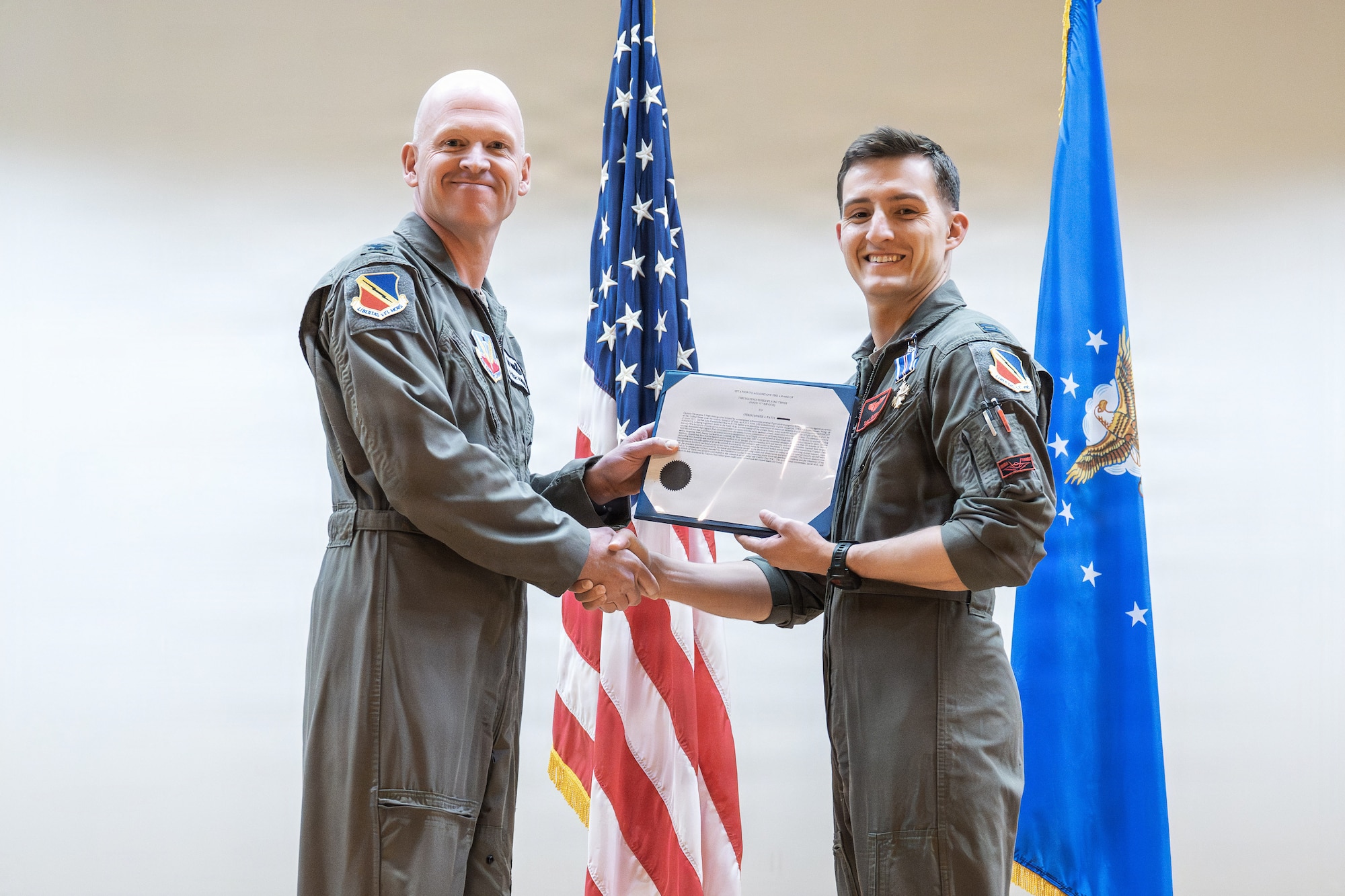 A photo of an Air Force officer presenting an award to another military member on stage.