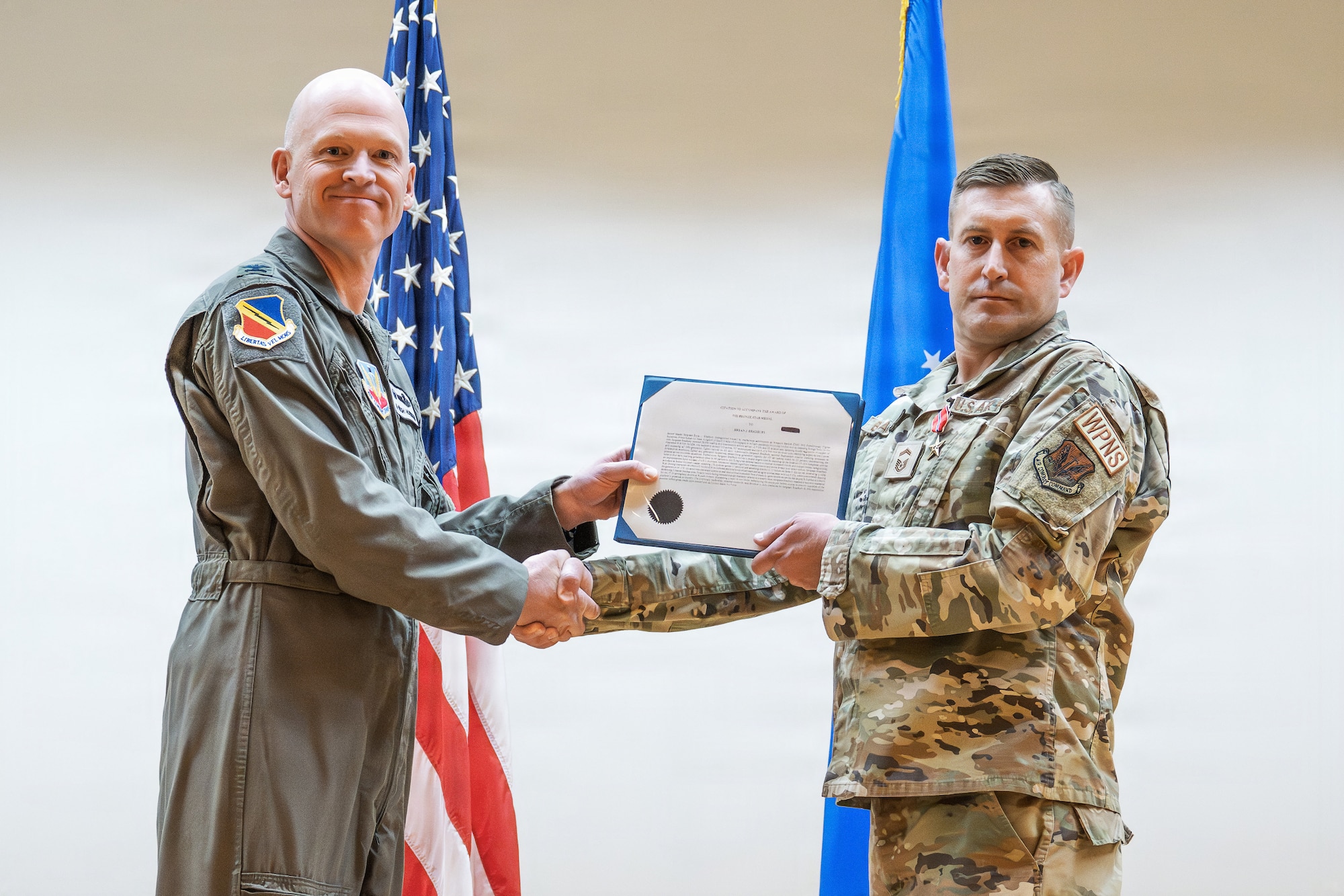 A photo of an Air Force officer presenting an award to another military member on stage.