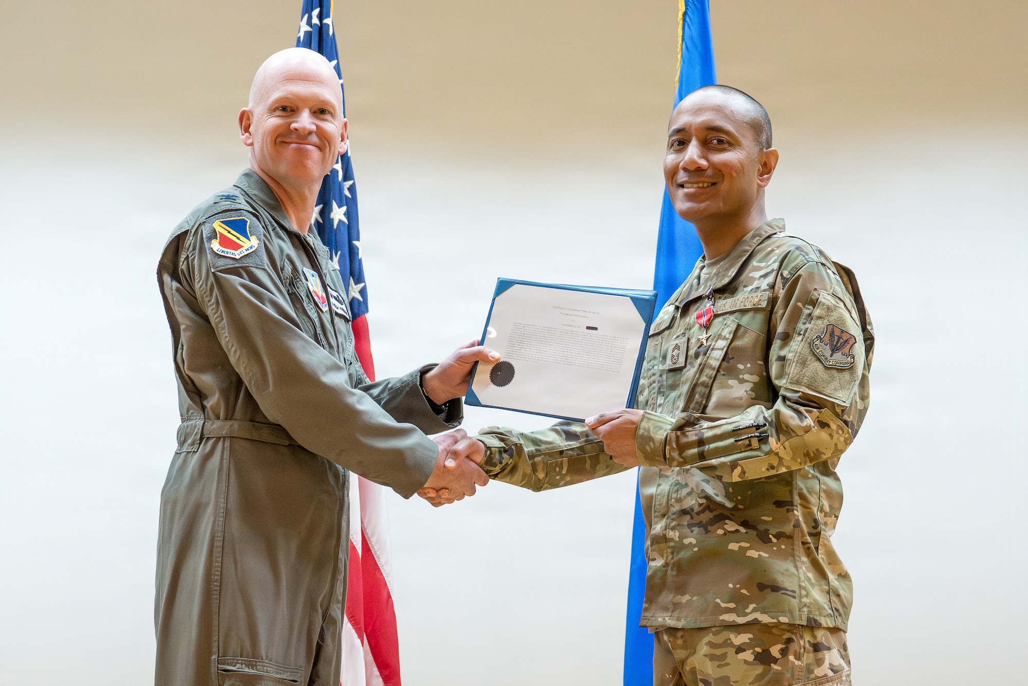 A photo of an Air Force officer presenting an award to another military member on stage.