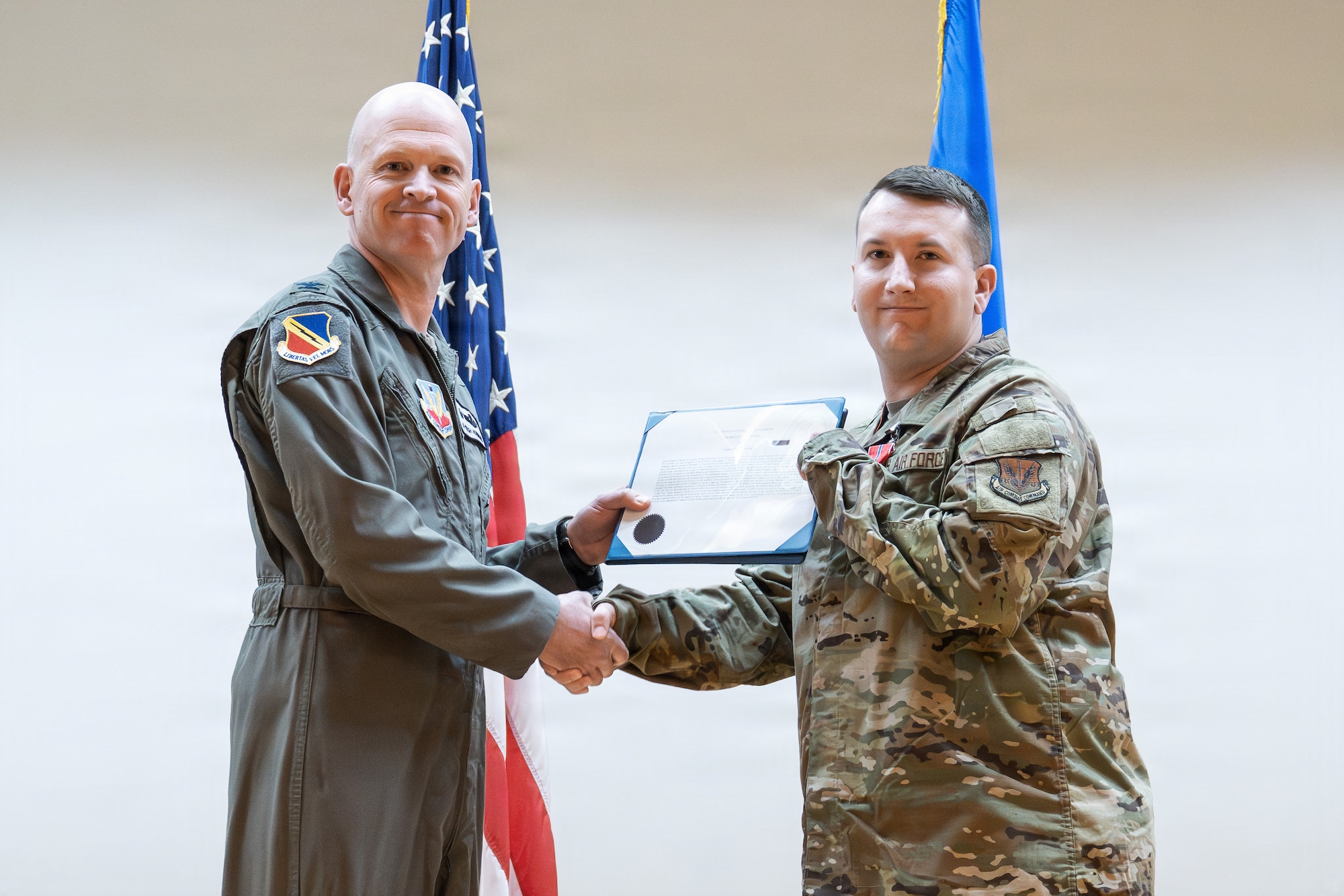 A photo of an Air Force officer presenting an award to another military member on stage.