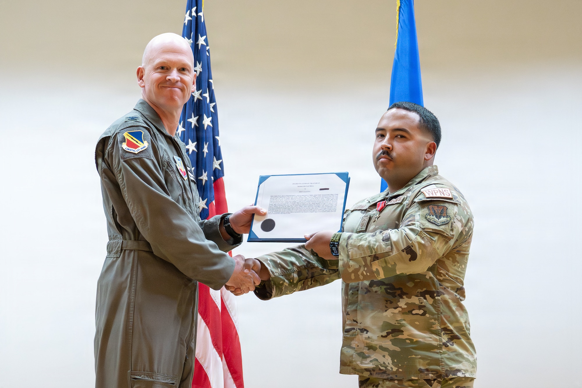 A photo of an Air Force officer presenting an award to another military member on stage.