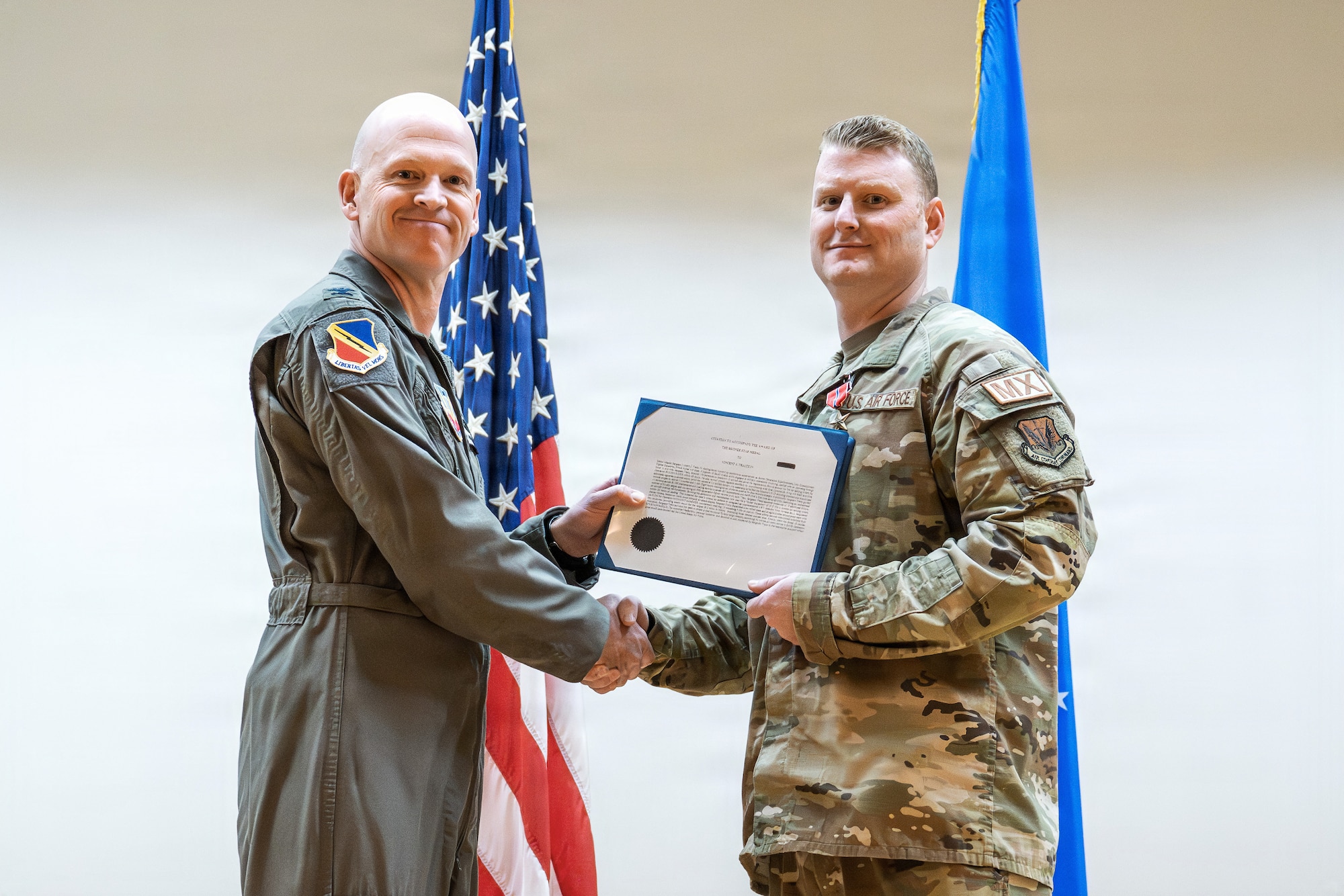 A photo of an Air Force officer presenting an award to another military member on stage.