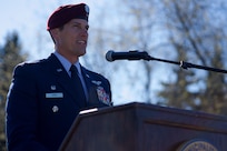 An Air Force officer speaks at a lectern outdoors.
