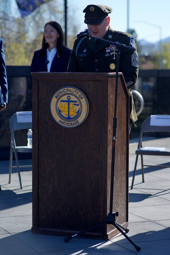 An Army Soldier speaks at a lectern outdoors.