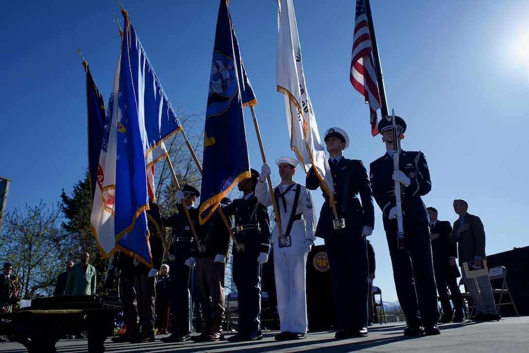 An Honor Guard presents U.S., Alaska, and military service colors.