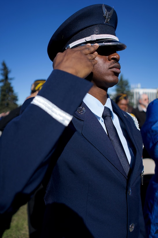 An Air Force Airman in dress blues salutes.