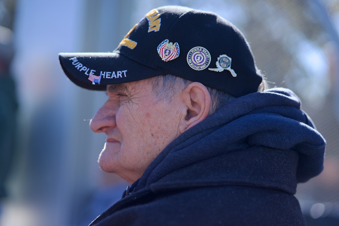 An older veteran with Vietnam War cap covered in military unit pins.