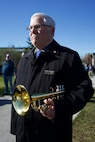 A bugler holding his bugle at the ready.