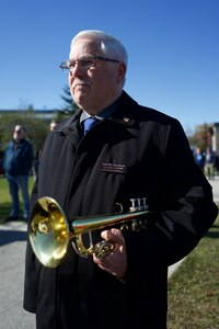 A bugler holding his bugle at the ready.