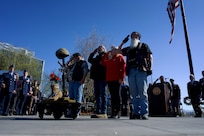 Veterans in biker outfits honoring a rifle, helmet, and dog tags memorial