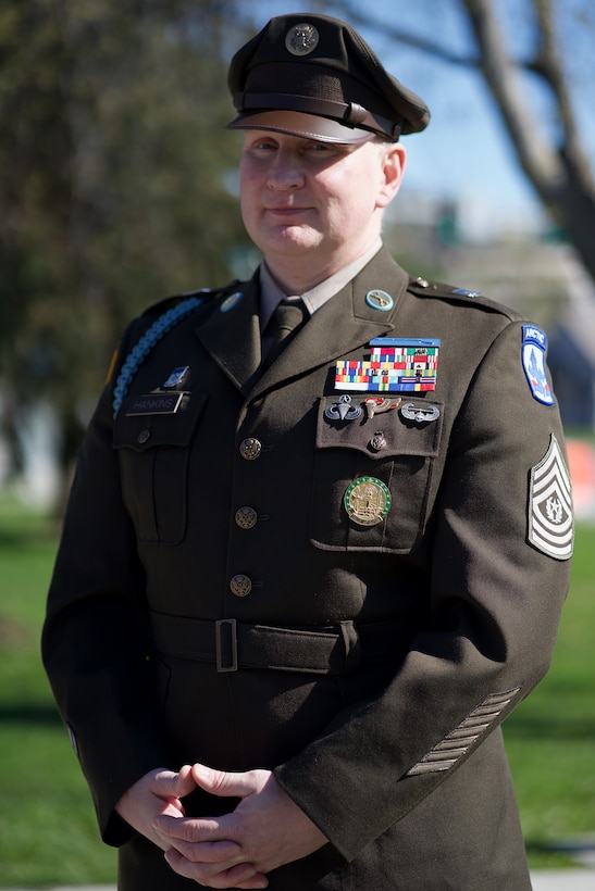 A decorated Army command sergeant major in dress green uniform.