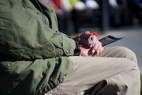 Veteran in military clothing holding a red poppy.
