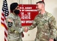 A man in an Army uniform shakes the hand of another man in an Army uniform in front of a large banner that reads "U.S. Army Corps of Engineers Emergency Operations."