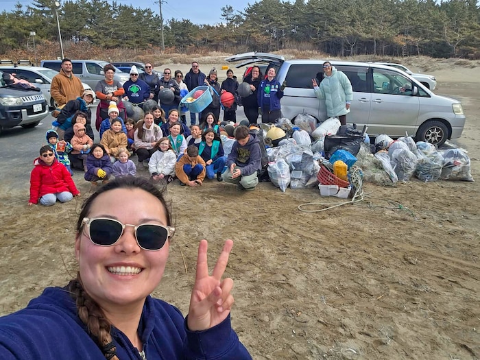 The Misawa Air Base Girl Scouts pose by a collection of buoys and trash after a beach cleanup.