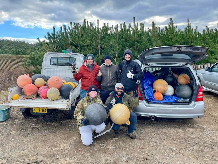 Volunteers pose next to recovered buoys during a beach cleanup.
