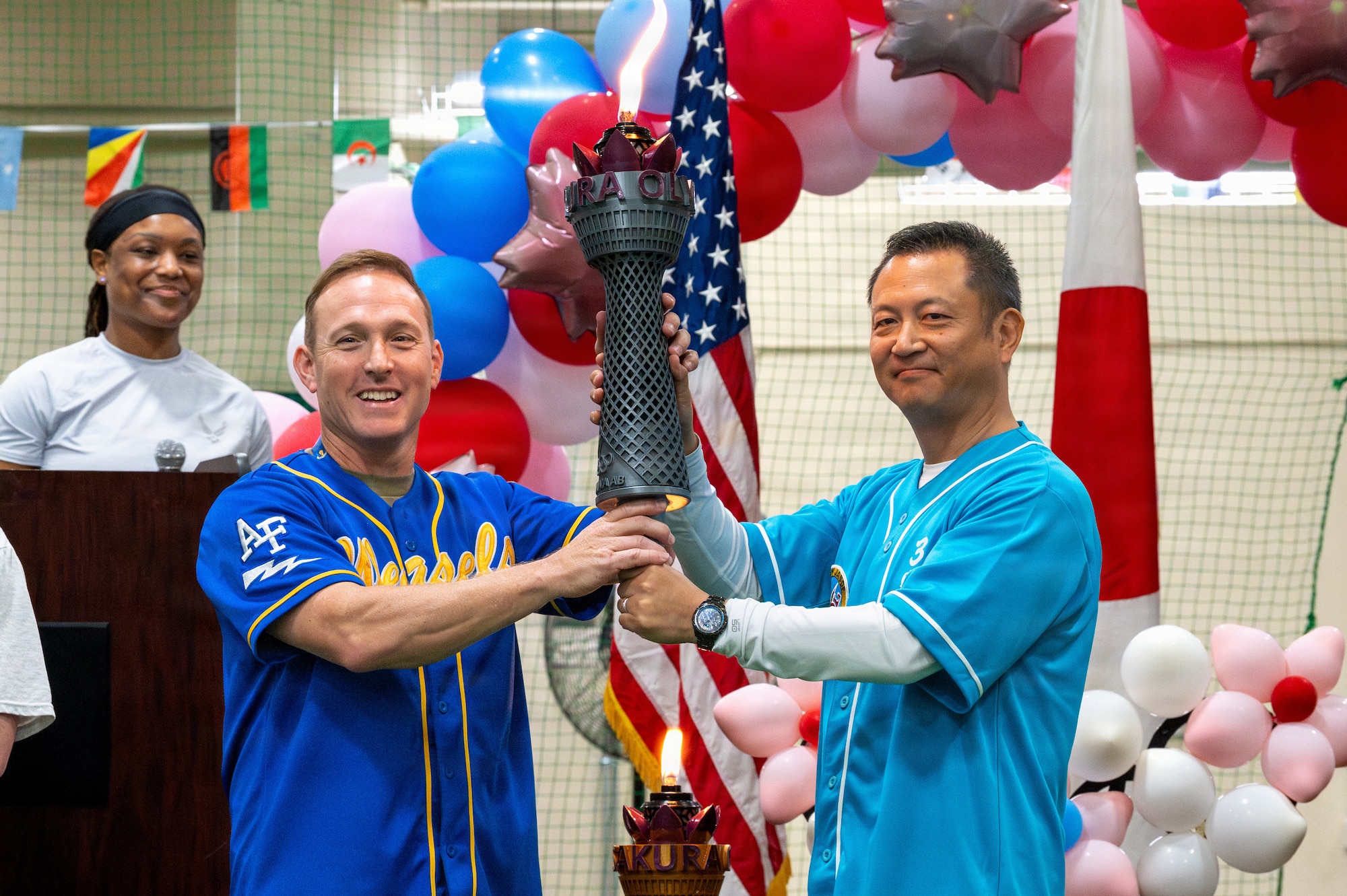 U.S. Air Force Col. Paul Davidson, 35th Fighter Wing commander, left, and Japan Air Self-Defence Force Maj. Gen. Teru Tomikawa, 3rd Air Wing commander, pass a ceremonial torch during the 2026 Sakura Olympics opening ceremony at Misawa Air Base, Japan, May 11, 2026.