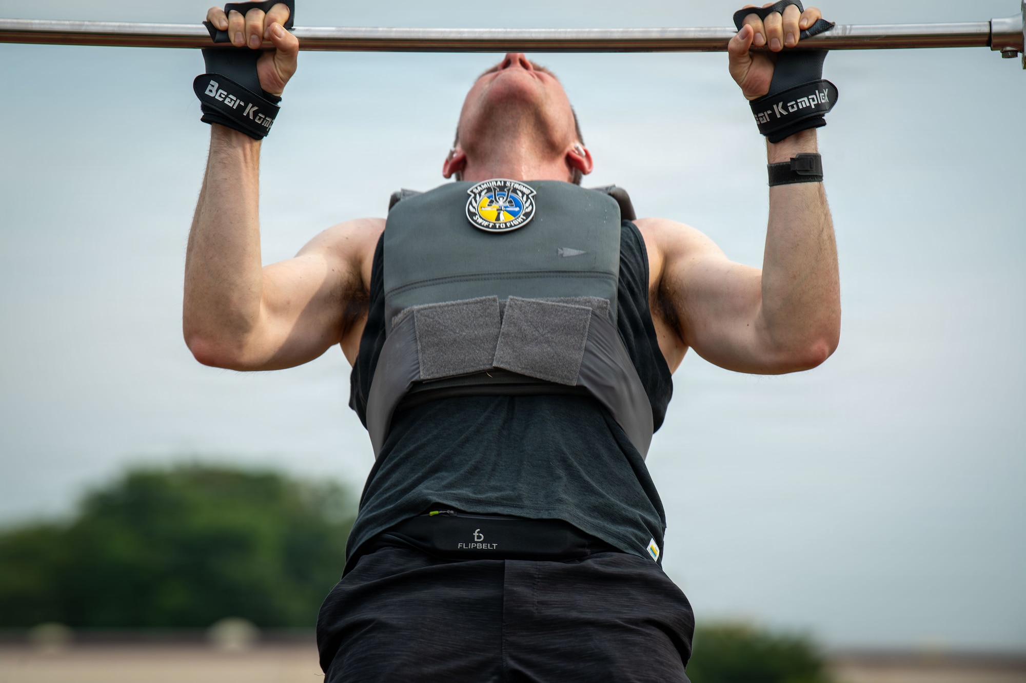 A man performs a pullup with a weighted vest on