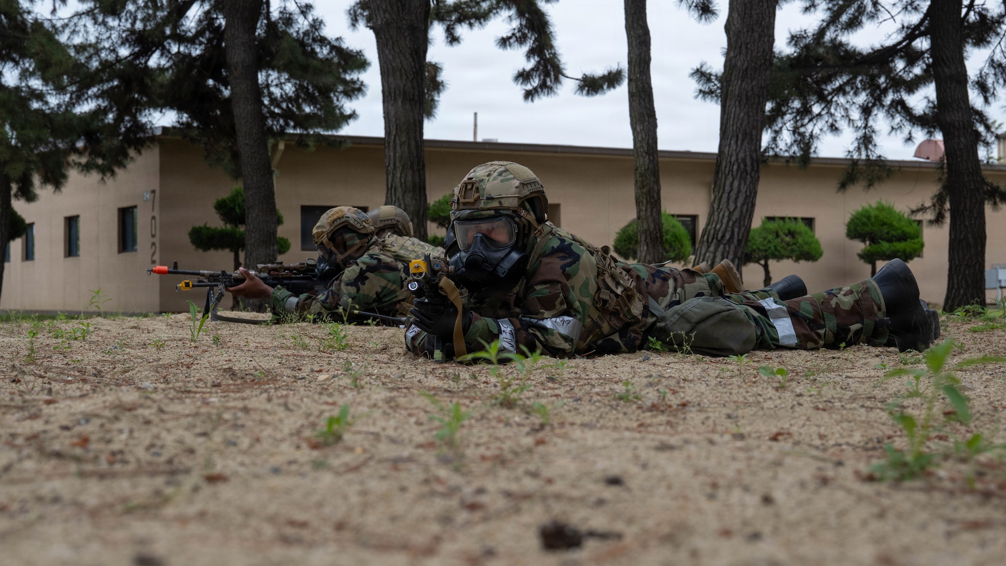 Airmen lay on ground with weapons.