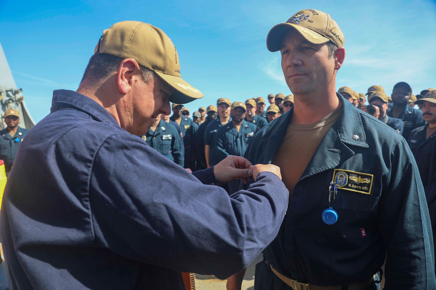 Capt. Alex Mamikonian (left), Naval Surface Group Europe, pins Cmdr. R. J. DaPrato, incoming commanding officer of USS Roosevelt (DDG 80), with the command-at-sea pin during a change of command ceremony on the flight deck of Roosevelt, May 22, 2026. Daprato relieved Cmdr. Jared L. Carlson from command of Roosevelt during the ceremony.