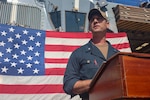 Cmdr. R. J. DaPrato, commanding officer of USS Roosevelt (DDG 80), make his first address to the crew, on the flight deck of Roosevelt, May 22, 2026. Daprato relieved Cmdr. Jared L. Carlson from command of Roosevelt during the ceremony.