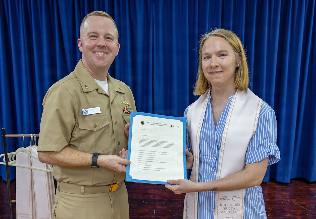 YOKOSUKA, Japan (May 21, 2026) — Cmdr. Mathew Burdick, director for Dental Services at U.S. Naval Hospital Yokosuka, presents a letter of completion to Alexis Cates during a Red Cross Dental Assistant Program recognition ceremony at U.S. Naval Hospital Yokosuka. The revitalized Red Cross Dental Assistant Program provides participants with more than 600 hours of classroom instruction, clinical observation and hands-on training while supporting patient care and workforce development within Navy Medicine. (U.S. Navy photo by Daniel Taylor/USNMRTC Yokosuka Public Affairs)