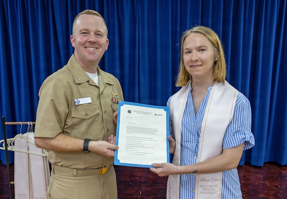 YOKOSUKA, Japan (May 21, 2026) — Cmdr. Mathew Burdick, director for Dental Services at U.S. Naval Hospital Yokosuka, presents a letter of completion to Alexis Cates during a Red Cross Dental Assistant Program recognition ceremony at U.S. Naval Hospital Yokosuka. The revitalized Red Cross Dental Assistant Program provides participants with more than 600 hours of classroom instruction, clinical observation and hands-on training while supporting patient care and workforce development within Navy Medicine. (U.S. Navy photo by Daniel Taylor/USNMRTC Yokosuka Public Affairs)