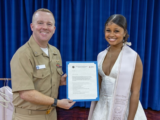 YOKOSUKA, Japan (May 21, 2026) — Cmdr. Mathew Burdick, director for Dental Services at U.S. Naval Hospital Yokosuka, presents a letter of completion to Amari Ewing during a Red Cross Dental Assistant Program recognition ceremony at U.S. Naval Hospital Yokosuka. The revitalized Red Cross Dental Assistant Program provides participants with more than 600 hours of classroom instruction, clinical observation and hands-on training while supporting patient care and workforce development within Navy Medicine. (U.S. Navy photo by Daniel Taylor/USNMRTC Yokosuka Public Affairs)