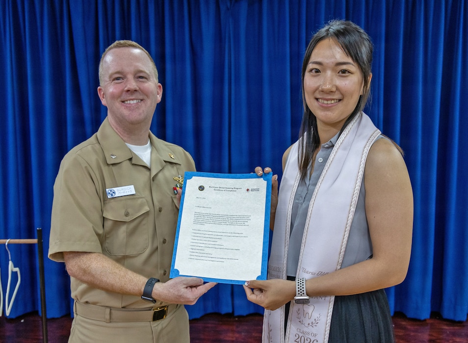 YOKOSUKA, Japan (May 21, 2026) — Cmdr. Mathew Burdick, director for Dental Services at U.S. Naval Hospital Yokosuka, presents a certificate of completion to Victoria Miller during a Red Cross Dental Assistant Program recognition ceremony at U.S. Naval Hospital Yokosuka. The revitalized Red Cross Dental Assistant Program provides participants with more than 600 hours of classroom instruction, clinical observation and hands-on training while supporting patient care and workforce development within Navy Medicine. (U.S. Navy photo by Daniel Taylor/USNMRTC Yokosuka Public Affairs)