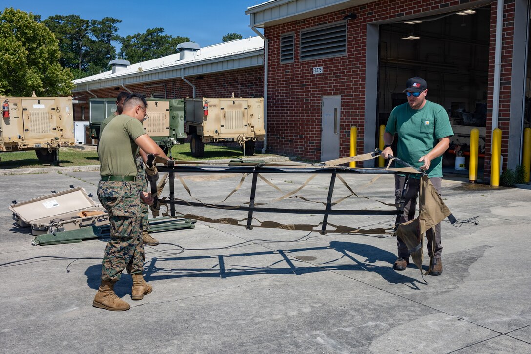U.S. Marine Corps Cpl. Duc Nguyen, left, a utilities systems technician with Combat Logistics Battalion 2, Combat Logistics Regiment 2, 2nd Marine Logistics Group, and Carl Lynn, a contractor with the Marine Corps Warfighting Lab, set up solar panels for a Hybrid Expeditionary Power trailer at Marine Corps Base Camp Lejeune, North Carolina, May 19, 2026. CLB-2 is field testing Marine Corps Warfighting Laboratory funded experimental capabilities to provide feedback on design changes and operational stability. (U.S. Marine Corps photo by Sgt. Rafael Brambila-Pelayo)