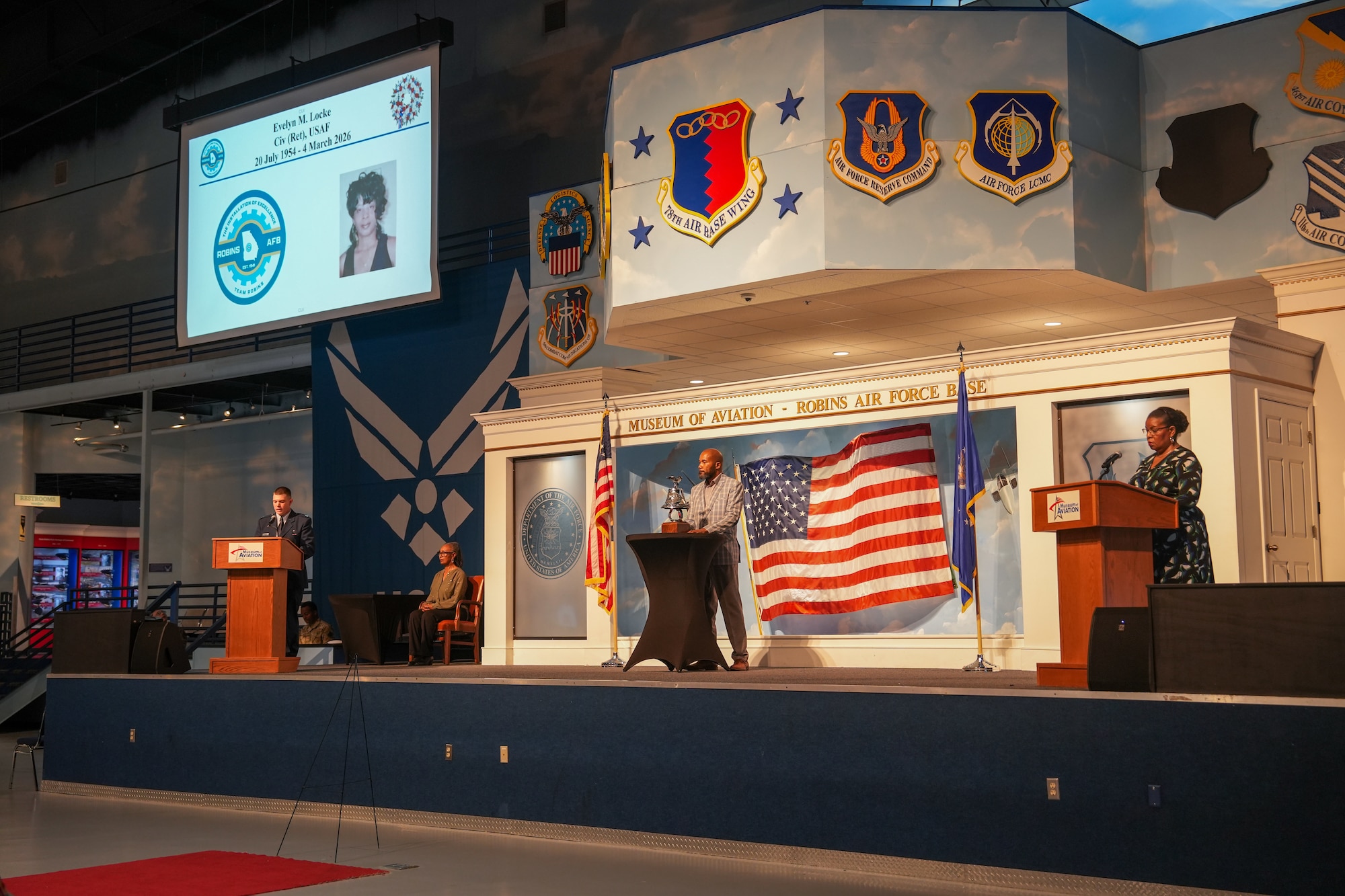Three people stand on stage