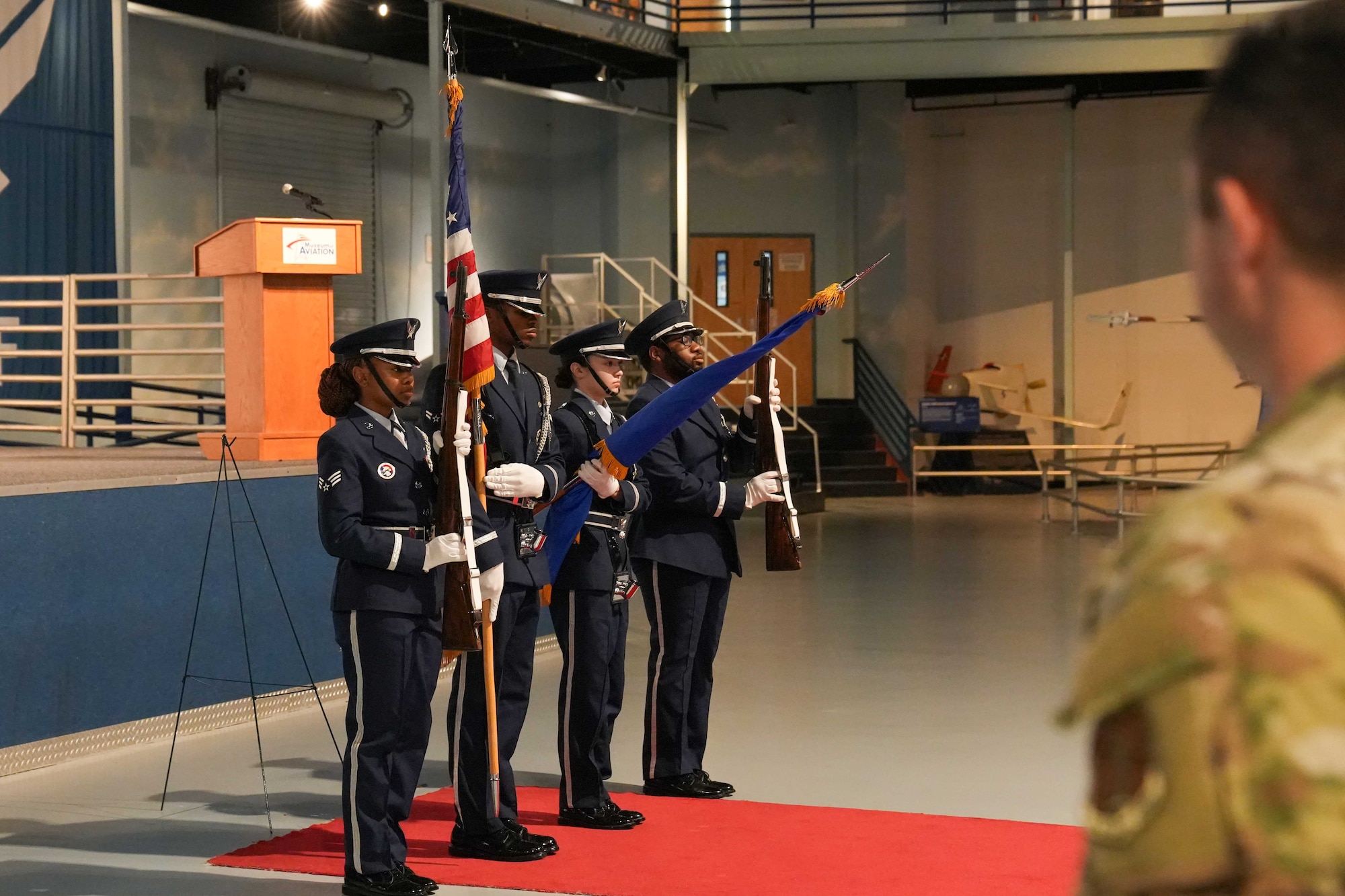 Military honor guard members present the colors in front of a stage