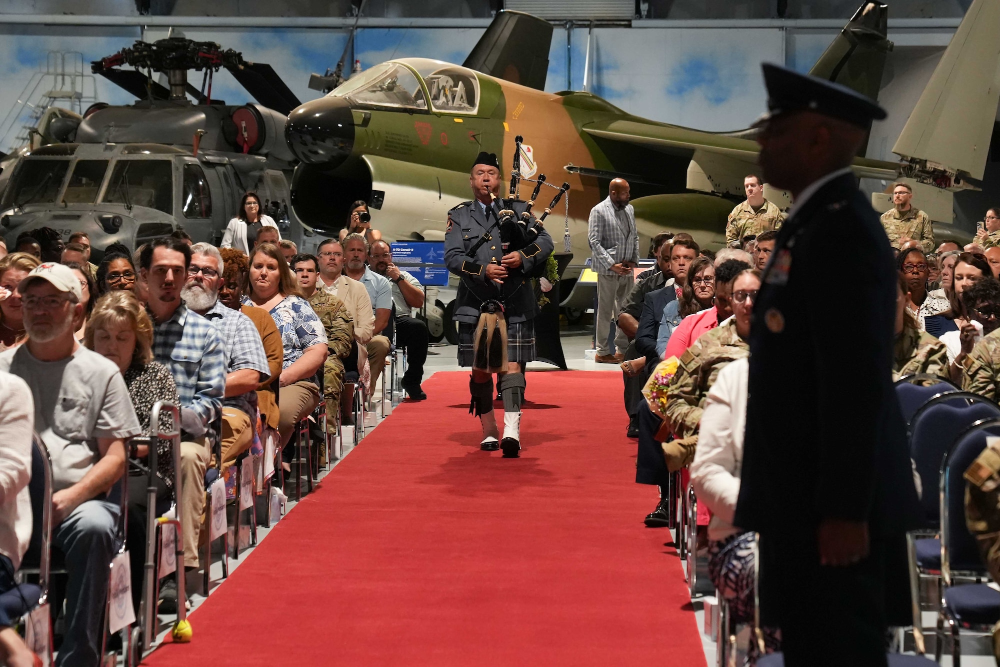 Man playing bag pipes walks down an aisle playing