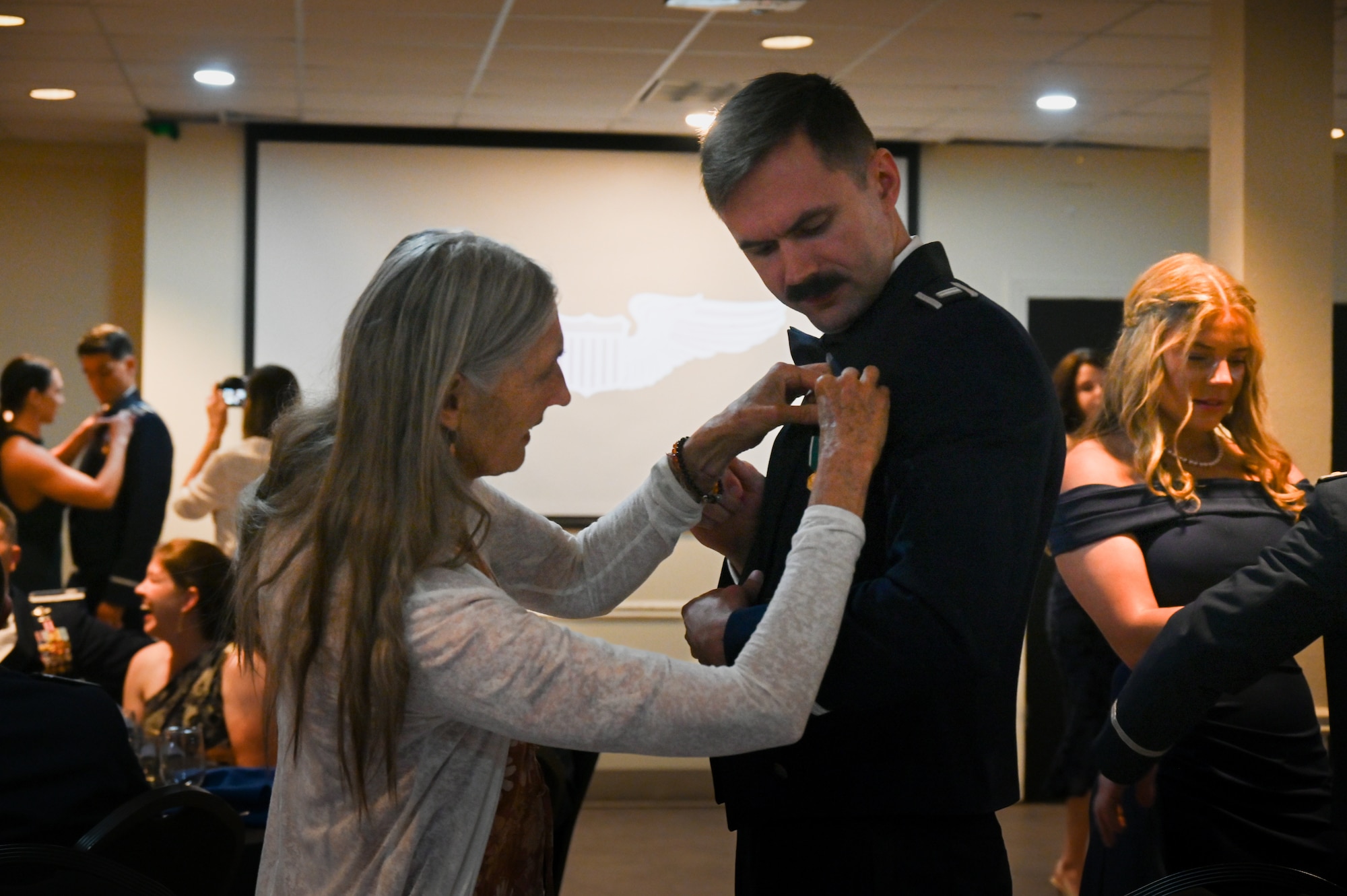 Loved ones pin silver wings on their graduate during a graduation ceremony of Class 26-11 at Laughlin Air Force Base, Texas, May 21, 2025. The breaking of silver wings is a tradition dating back to the U.S. Army Air Corps where a pilot's first wings are not to be worn but broken and given to a loved one. (U.S. Air Force photo by Airman 1st Class Kylie Rabb)