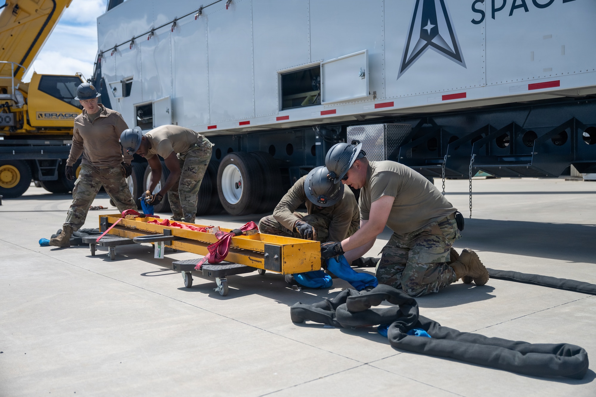 Air Force troops attach slings to a load spreader bar.