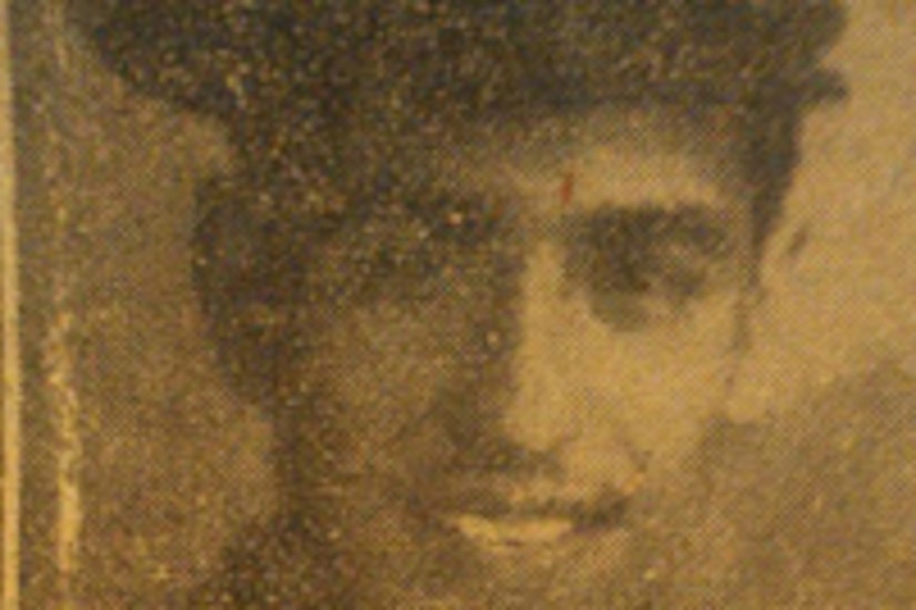 A man in a formal military uniform smiles for a portrait.
