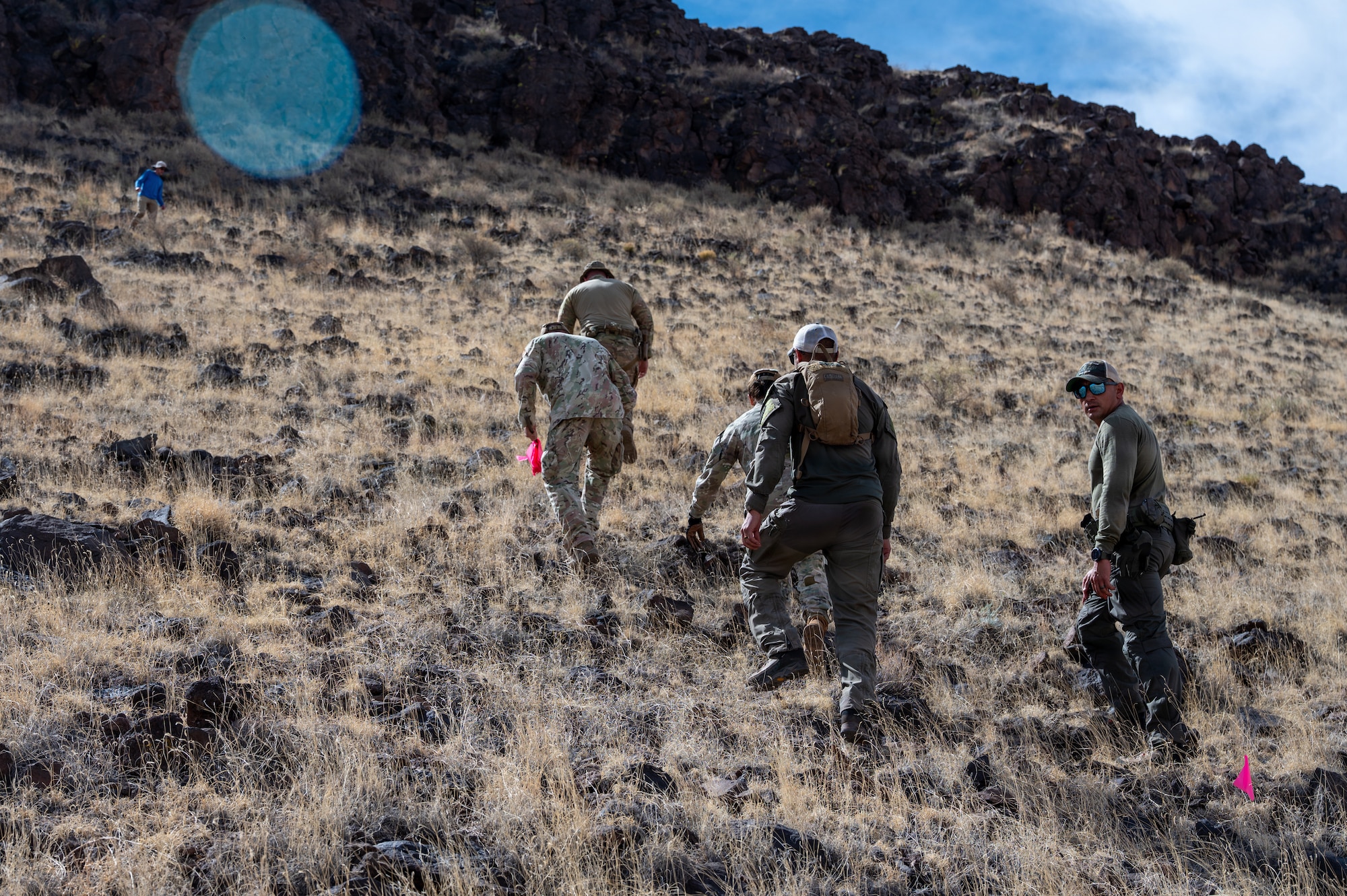 Members assigned to the 377th Explosive Ordnance Disposal team and New Mexico State Police Explosive Ordnance Disposal climb rugged terrain during a joint unexploded ordnance response operation at the Pueblo of Acoma, New Mexico, May 20, 2026. The teams worked together to locate and safely dispose of two unexploded World War II-era ordnance items while coordinating with environmental officials, New Mexico Fish and Wildlife personnel, and Pueblo of Acoma representatives to minimize impacts to local wildlife and the surrounding environment. (U.S. Air Force photo by Senior Airman Donnell Schroeter)