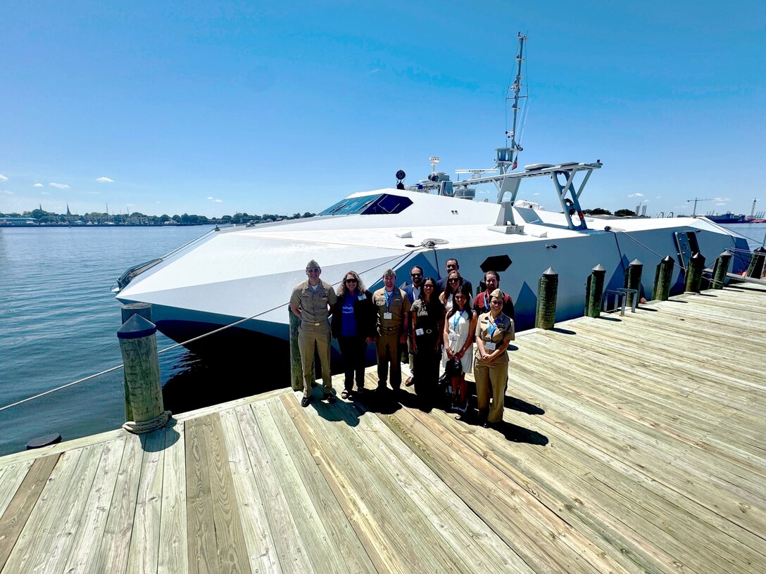 Members of the Mid-Atlantic Tech Bridge and 757 Defend and industry, making up the Defense Technology Accelerator cohort, pose in front of the Navy’s Stiletto demonstration platform along with Naval Surface Warfare Center Carderock Division Commanding Officer Capt. Chris Matassa on May 12 at the Norfolk, Va., downtown waterfront. Stiletto was on display for tours during the Department of the Navy Digital Warfighting Symposium.